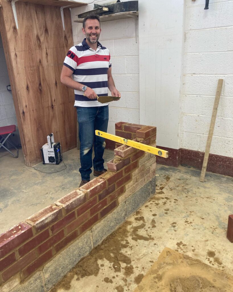 Bricklaying Course: A happy student levelling off and checking brick Course with a spirit level